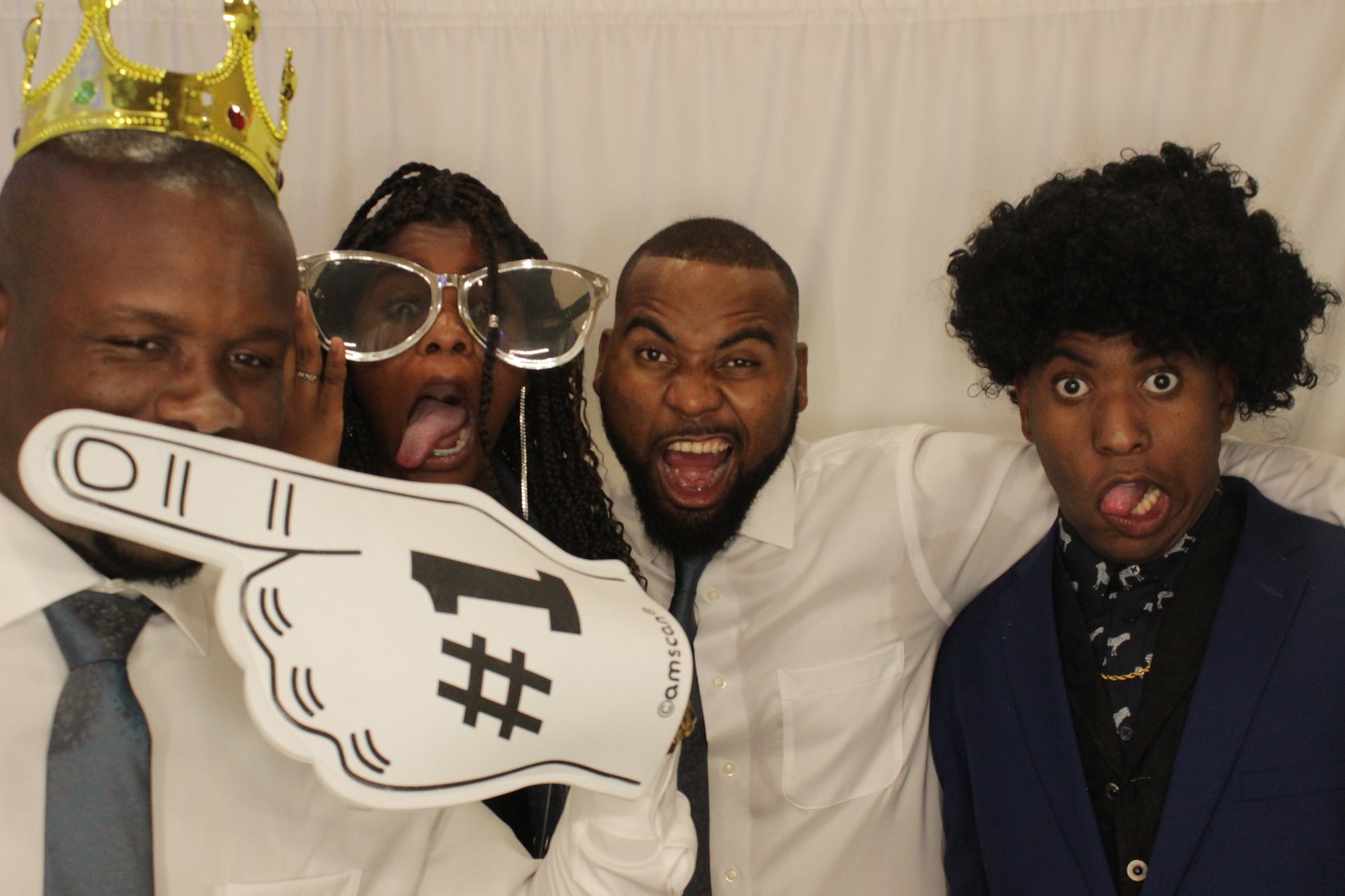 Four guests making playful expressions with oversized photo booth props
