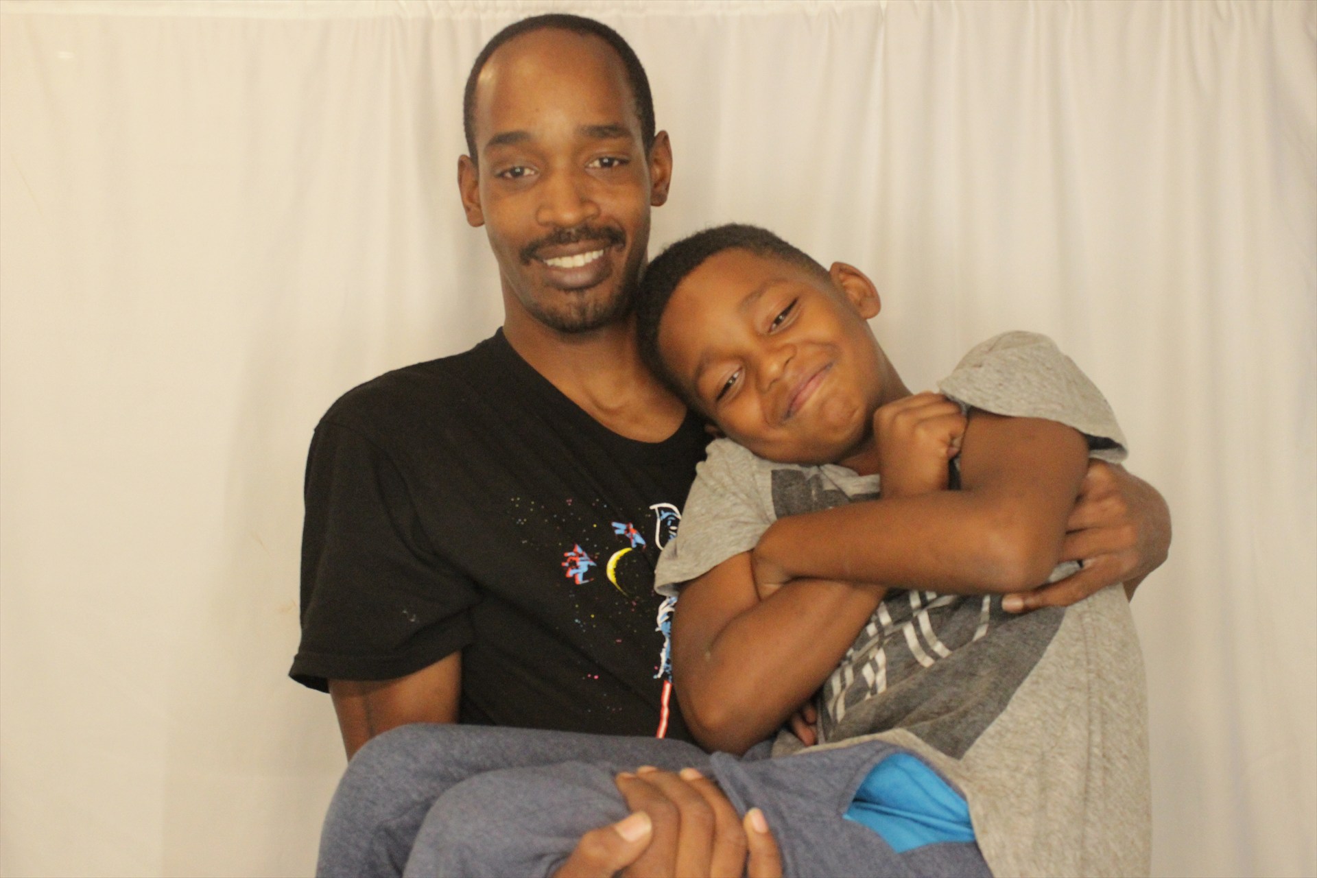 An adult holding a smiling child in front of a photo booth backdrop