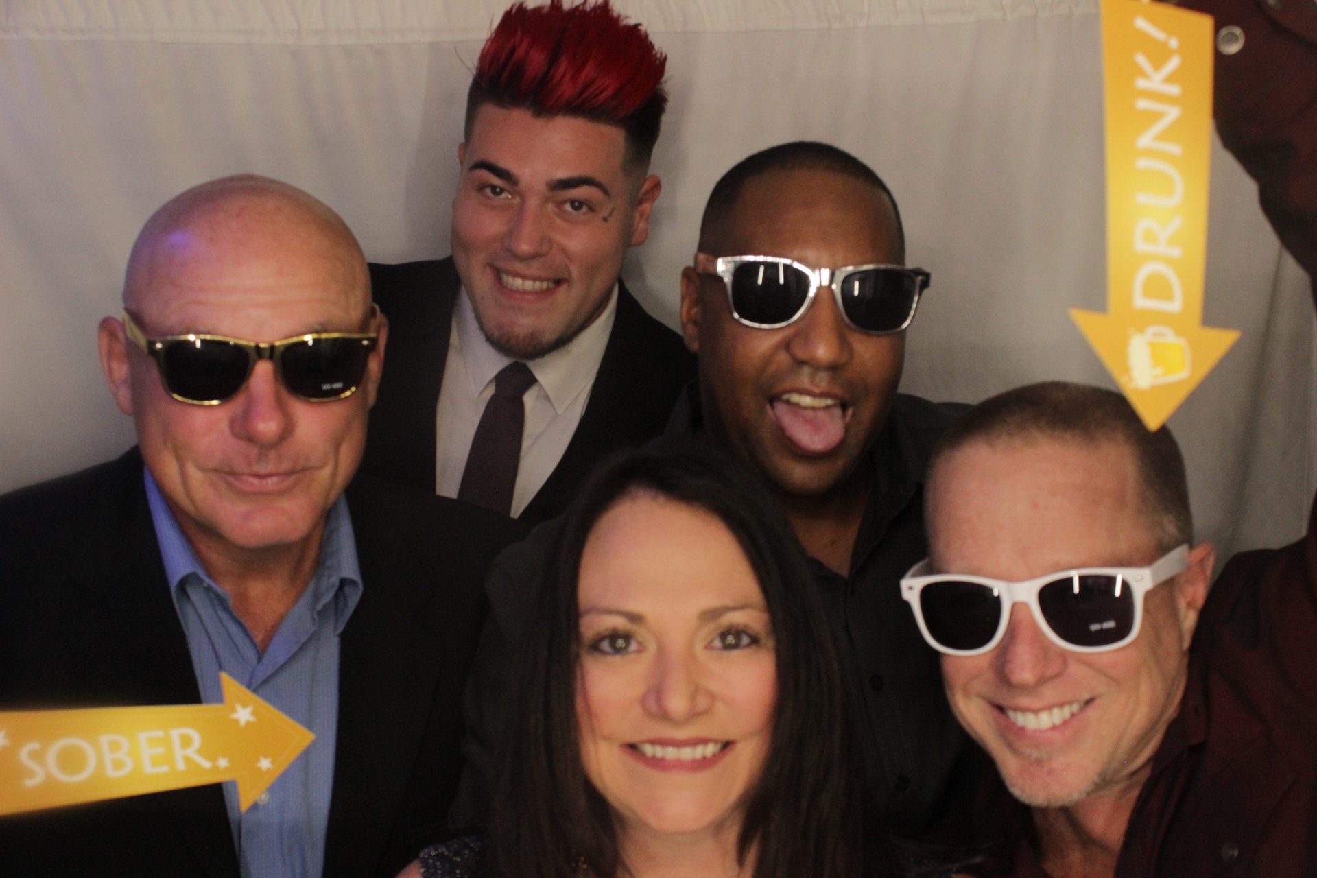Five guests posing together in sunglasses with New Year signs
