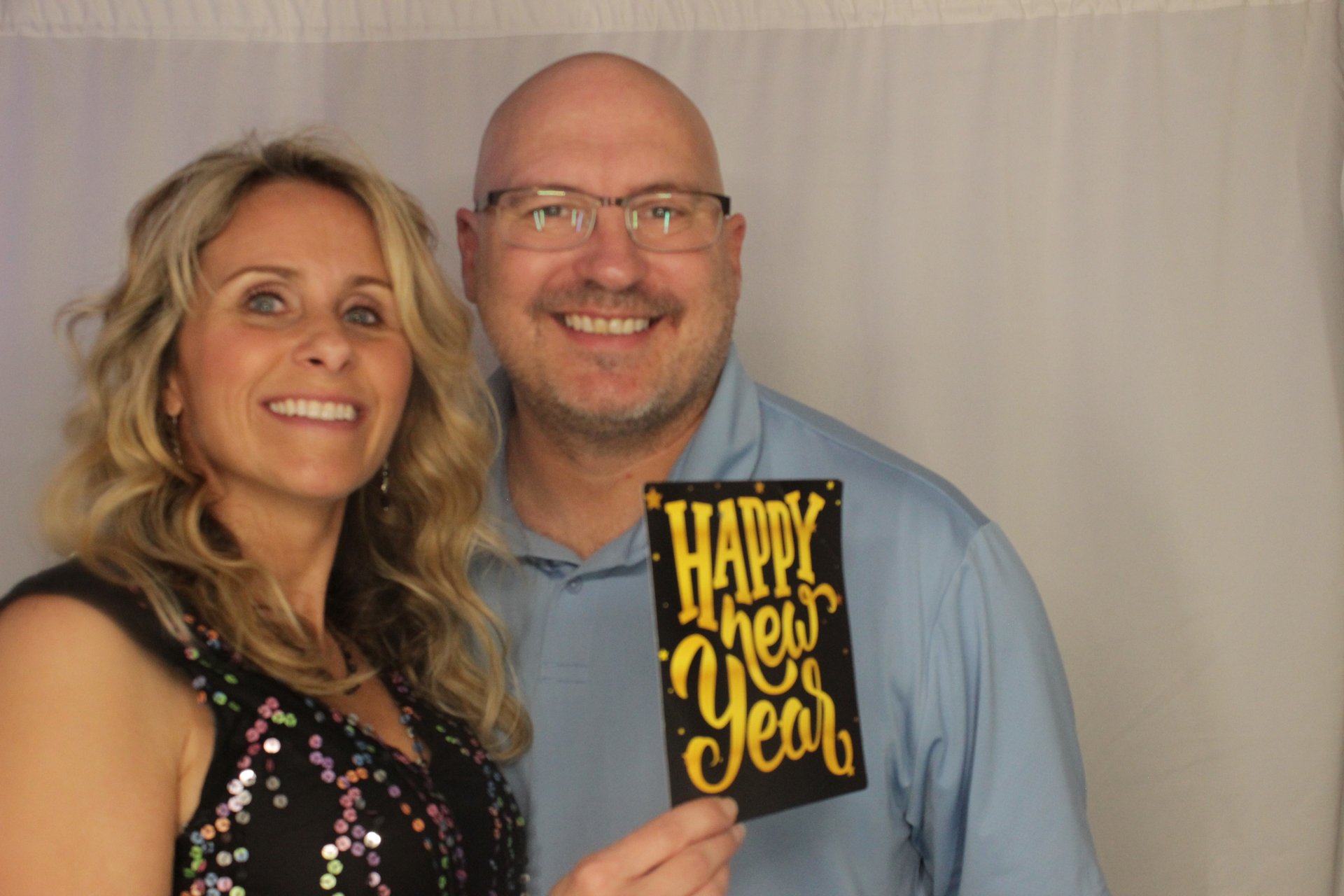 A smiling couple holding a Happy New Year sign