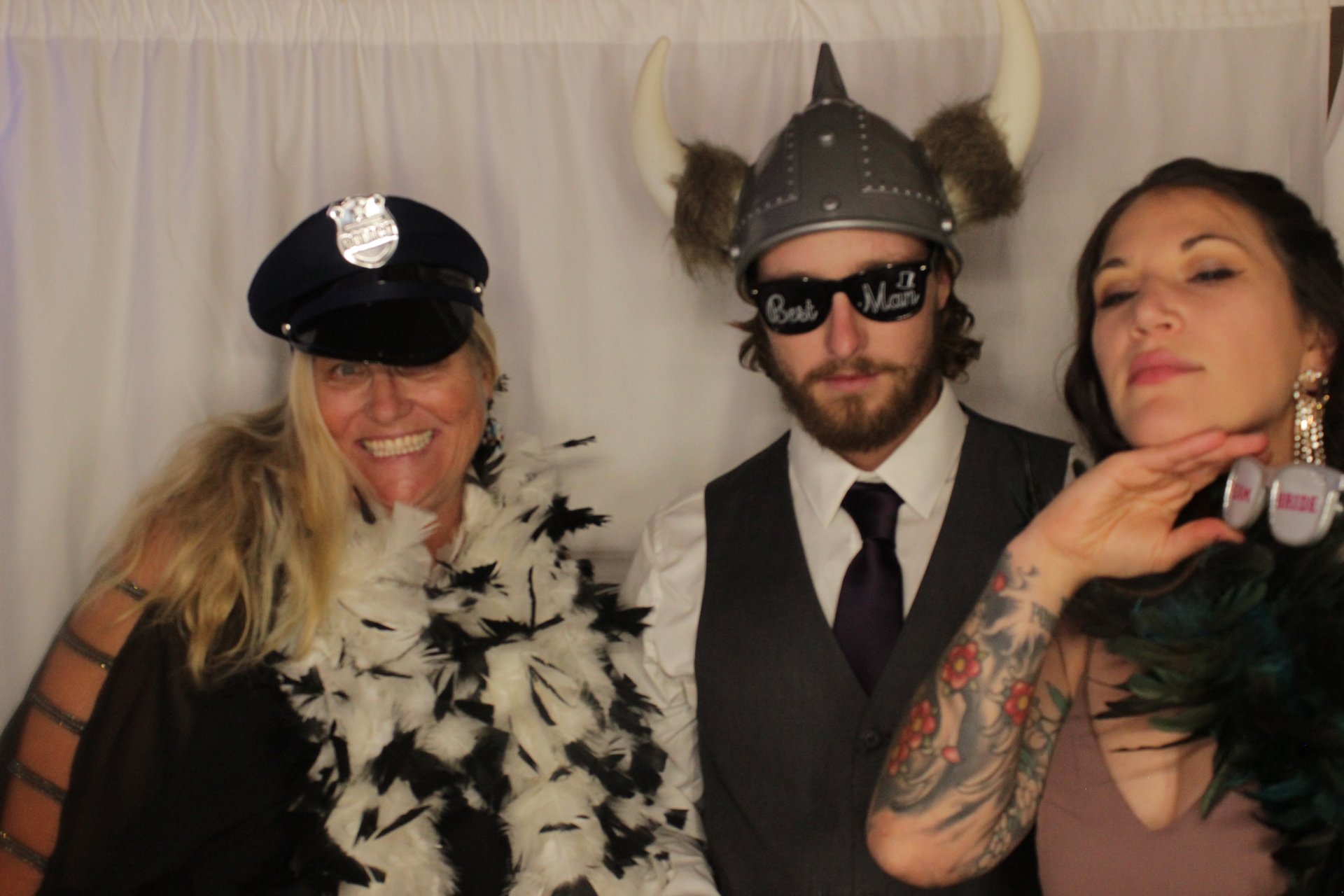 Three wedding guests posing with hats, sunglasses, and feather boas