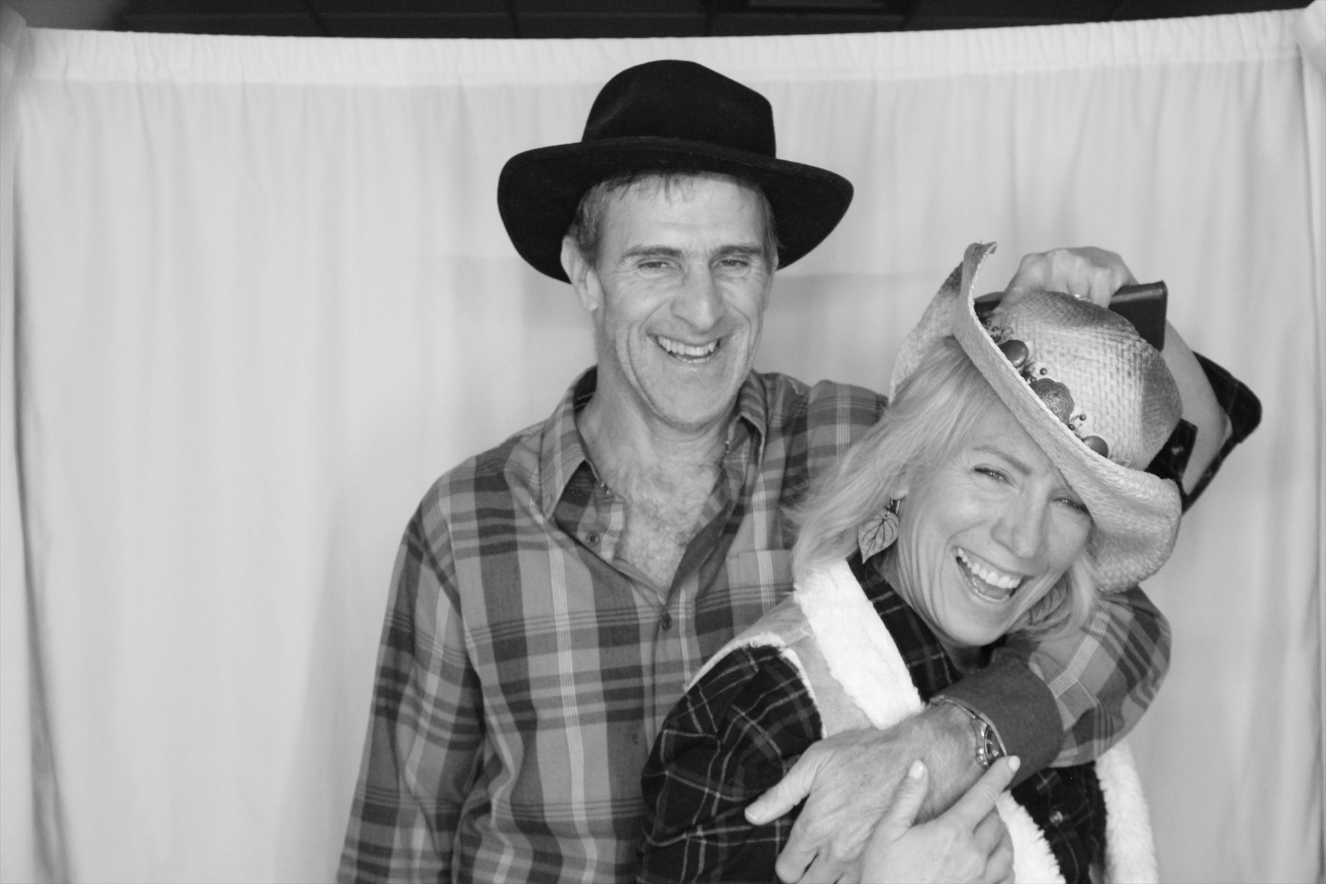 Laughing couple posing together in cowboy hats at the photo booth