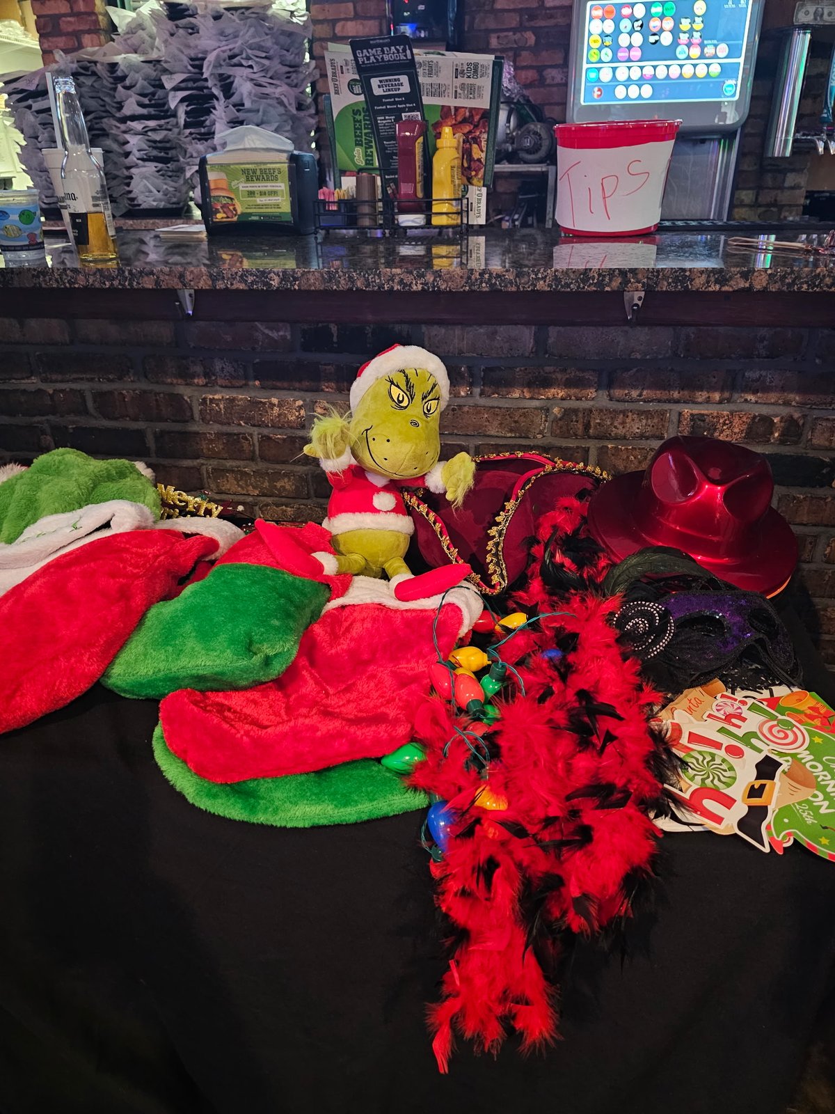 A table filled with Christmas photo booth hats, feather boas, lights, and Grinch props