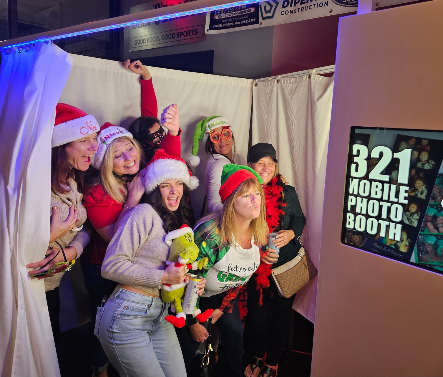 A group of guests celebrating in Christmas hats beside the photo booth